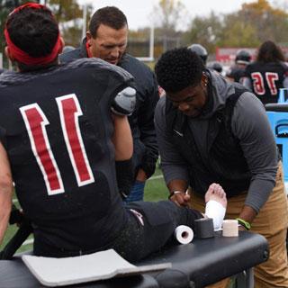 A student binds a football player's foot